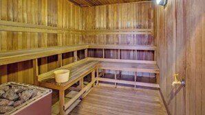Un sauna avec des bancs en bois et un bassin en pierre.