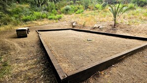 A square outdoor area with a central drain, surrounded by a wooden border.