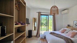 A bedroom with a bed, a wardrobe, a television, a mirror, and a view of the outdoors.