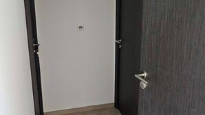 A narrow hallway with a tiled floor, two closed doors, and a light switch on the wall.