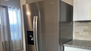 A stainless steel refrigerator in a kitchen with white cabinets and a granite countertop. - Marvelous 4-bedroom house in Houston with large backyard in quite neighborhood (Houston)