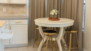 A modern kitchen with white cabinets, a round table with stools, a hanging light fixture, and a window with curtains. - Marvelous 4-bedroom house in Houston with large backyard in quite neighborhood (Houston)