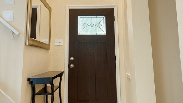 A hallway with a dark wooden door, a small table, a bench, and a chandelier. - Marvelous 4-bedroom house in Houston with large backyard in quite neighborhood (Houston)