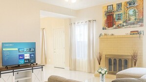 A living room with a beige sofa, a television on a stand, a fireplace, and a ceiling fan. - Marvelous 4-bedroom house in Houston with large backyard in quite neighborhood (Houston)