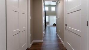 A hallway with white doors, wooden flooring, and a ceiling light.
