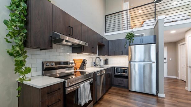 A modern kitchen with dark wood cabinets, stainless steel appliances, and a wooden countertop.