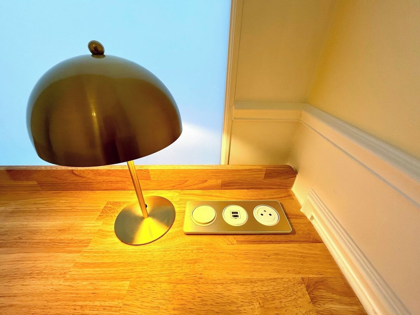 A desk lamp with a metallic shade and a power strip with three sockets.
