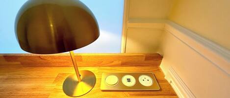 A desk lamp with a metallic shade and a power strip with three sockets.