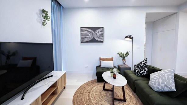 A modern living room with a sofa, a coffee table, a TV, and a painting on the wall. - KozyGuru | Box Hill | Chic and Close to It All (Box Hill)