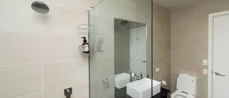 Ein modernes Badezimmer mit Duschkabine aus Glas, zwei Waschbecken und einer Toilette.