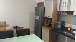 Uma cozinha compacta com geladeira, pia e área de refeições com mesa e cadeiras.