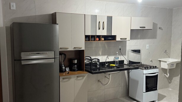 Uma cozinha moderna com frigorífico de aço inoxidável, forno embutido e uma pia.