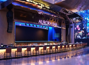 A bar area with a neon sign, bar counter, and seating.