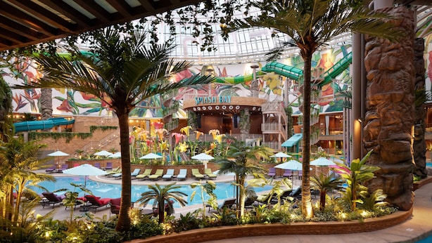 An indoor pool area with lounge chairs, palm trees, and a mural. - Inspire Entertainment Resort (Incheon)