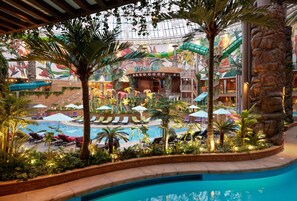 An indoor pool area with lounge chairs, palm trees, and a mural. - Inspire Entertainment Resort (Incheon)