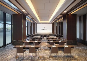 A conference room with a large screen displaying 'INSPIRE', rows of tables and chairs, and a patterned carpet. - Inspire Entertainment Resort (Incheon)