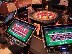 A casino gaming area with multiple slot machines and a roulette table.