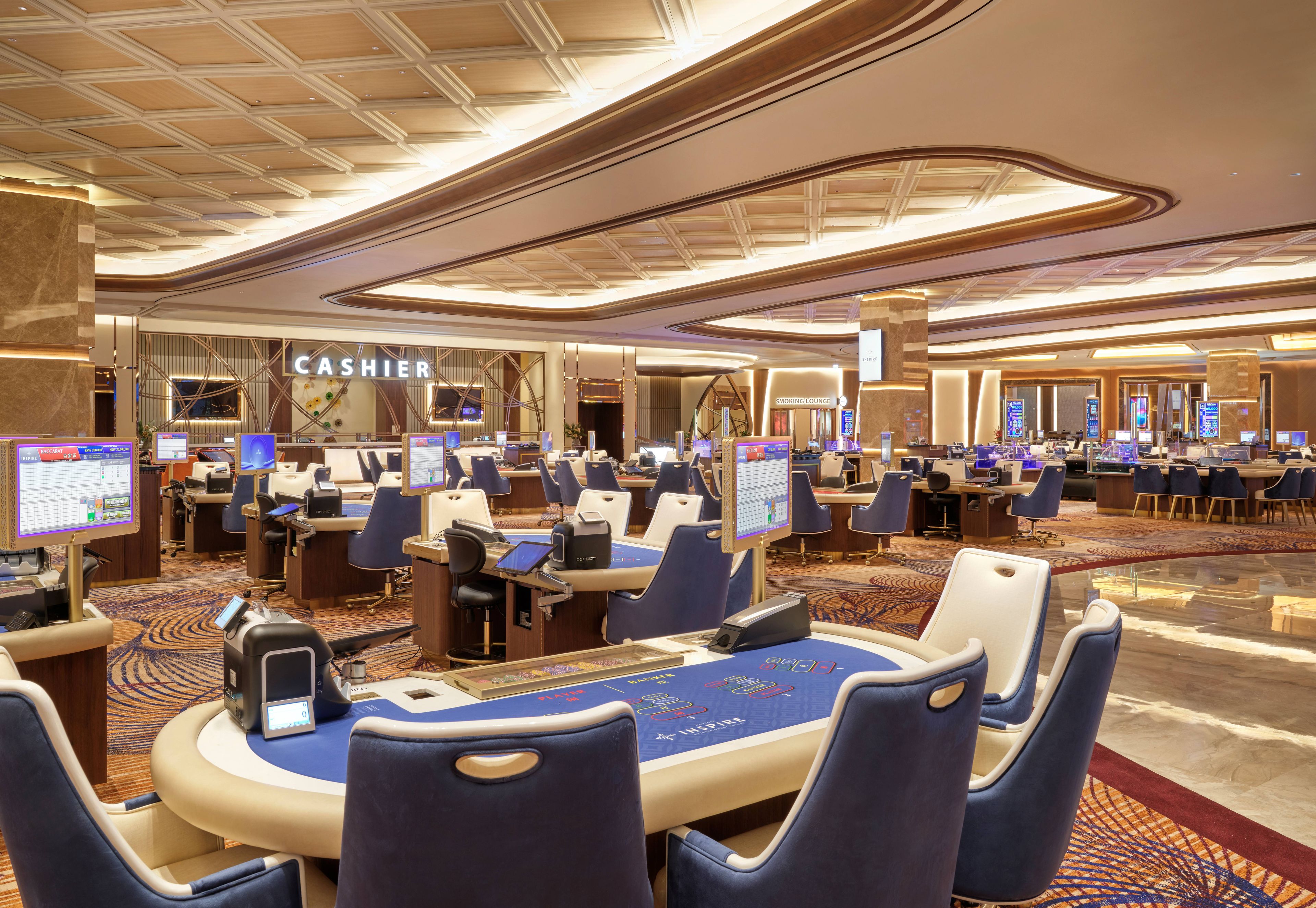A spacious hotel lobby with multiple self-service kiosks, a cashier area, and a variety of seating arrangements.