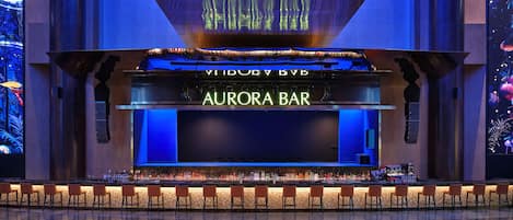 A bar with a neon sign, bar stools, and a large screen.