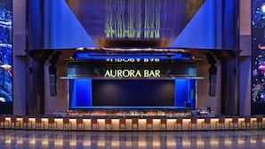 A bar with a neon sign, bar stools, and a large screen. - Inspire Entertainment Resort (Incheon)