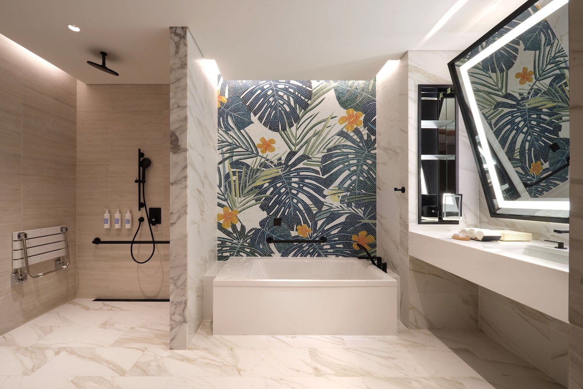 A modern bathroom with a bathtub, a shower, and a vanity with a mirror.