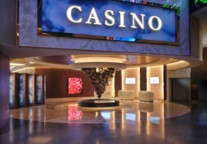 Un vestíbulo moderno con un cartel que dice 'CASINO', una lámpara central y un mostrador de recepción.