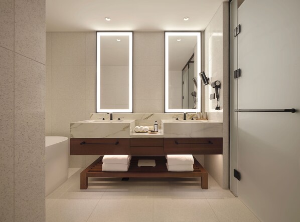 Un baño moderno con dos lavamanos, un espejo grande y un banco con toallas.