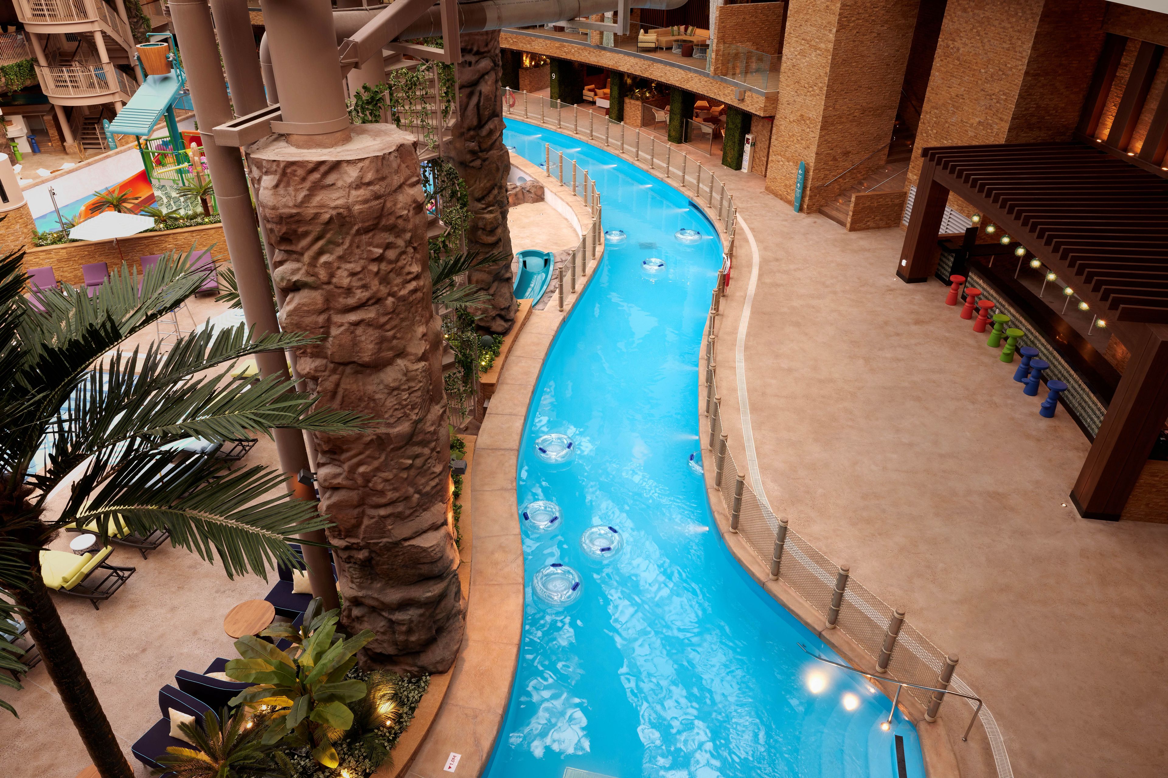 An indoor water slide pool with seating areas and a bar.