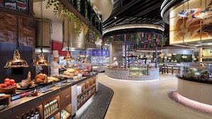 A modern restaurant interior with a central counter, hanging plants, and a decorative ceiling. - Inspire Entertainment Resort (Incheon)