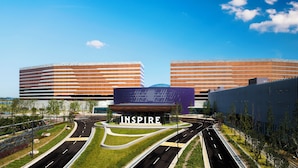 A modern building complex with 'INSPIR' signage, multiple entry points, and a central plaza with landscaped areas. - Inspire Entertainment Resort (Incheon)