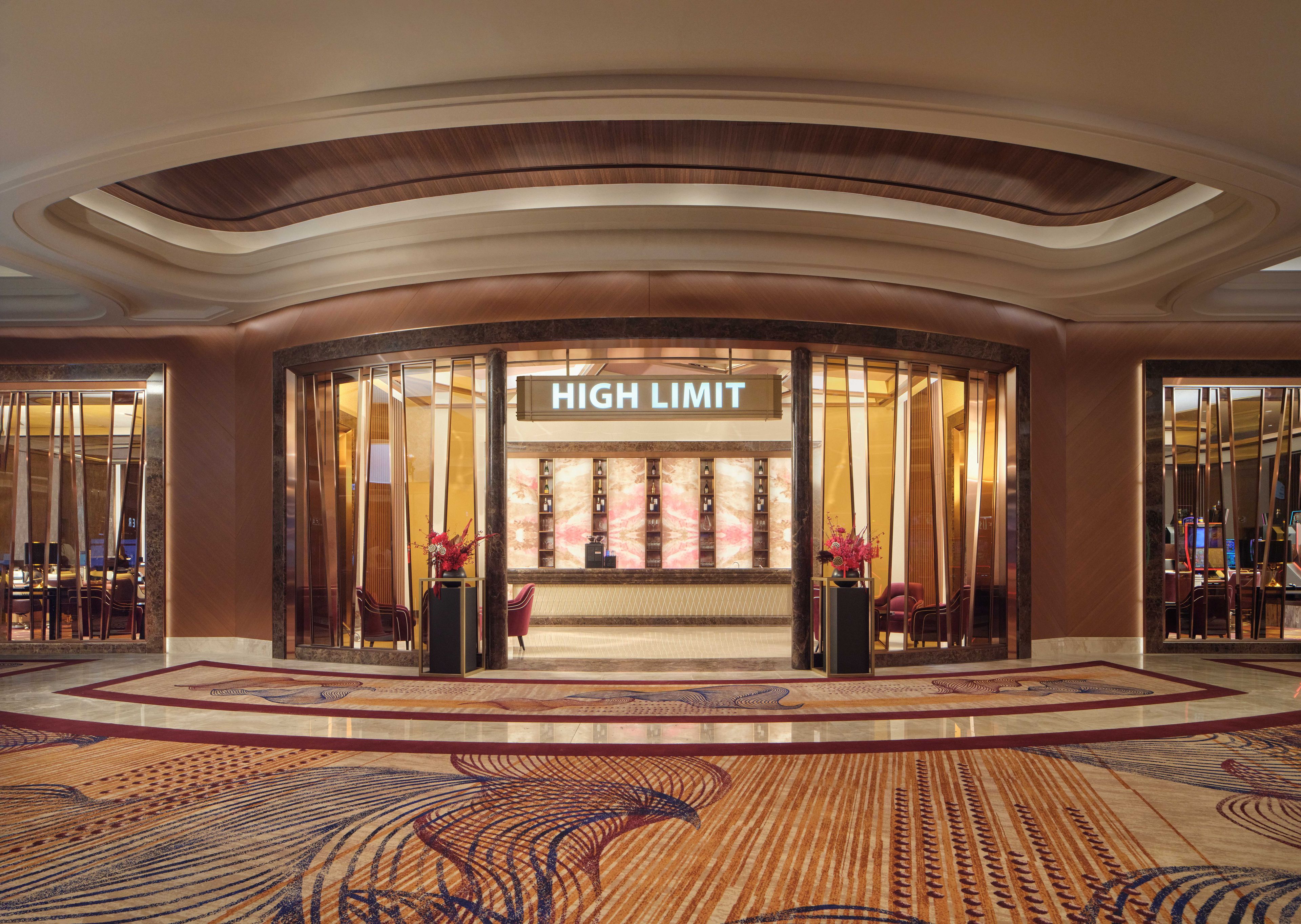 A hotel lobby with a curved entrance, a 'HIGH LIMIT' sign, and a patterned carpet.