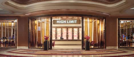 Et hotel lobby med en buet indgang, et skilt med teksten 'HIGH LIMIT' og et mønstret tæppe.