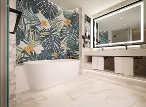 A modern bathroom with a freestanding bathtub, a large mirror, and a decorative leaf-patterned wall. - Inspire Entertainment Resort (Incheon)