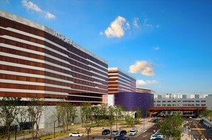 A modern hotel with a prominent 'INSPIRING' sign, a pedestrian bridge, and a parking area. - Inspire Entertainment Resort (Incheon)
