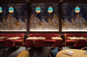 A restaurant with red seating, tables with white tableware, and wall murals of animals. - Inspire Entertainment Resort (Incheon)