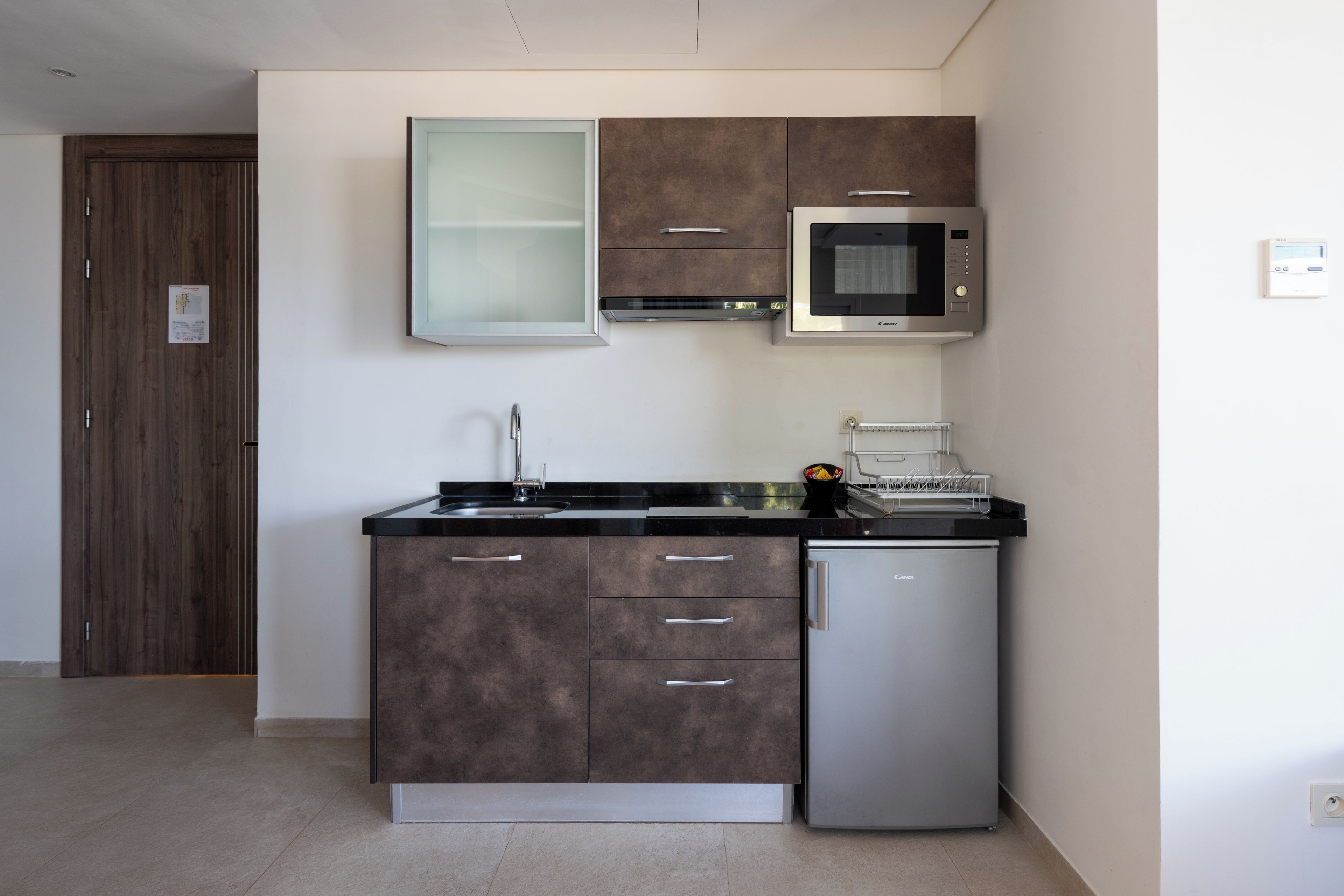 Una cucina moderna con forno a microonde integrato, frigorifero in acciaio inossidabile e un lavello a due vasche.
