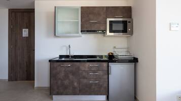 Una cocina moderna con microondas integrado, refrigerador de acero inoxidable y un lavamanos doble.