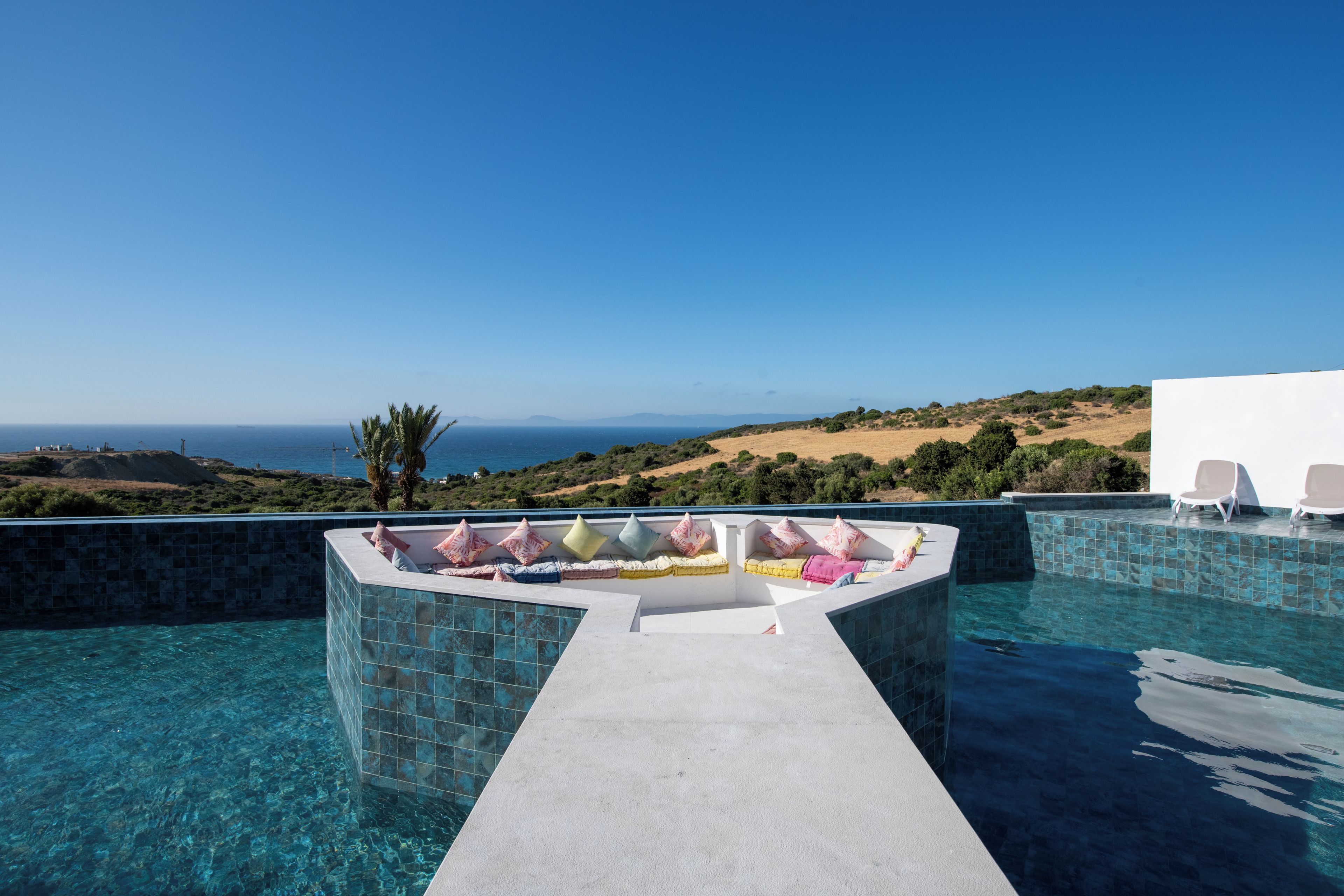 A swimming pool with a view of the sea and hills.