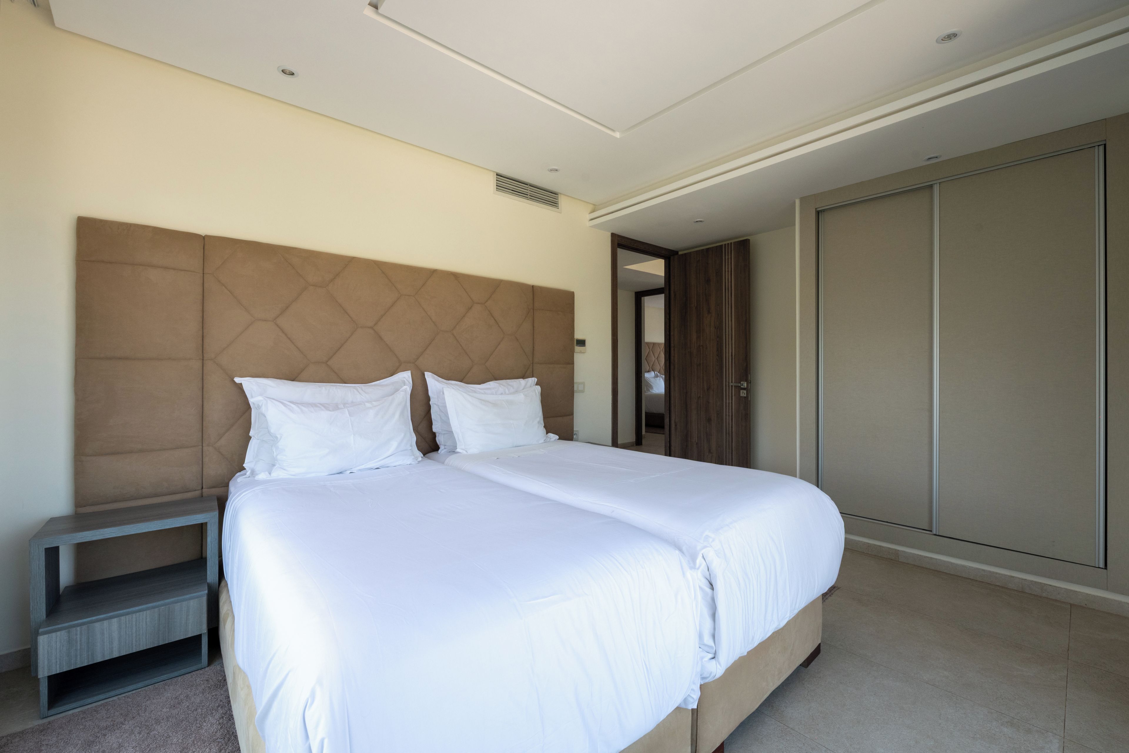 Una habitación de hotel moderna con una cama grande, una mesita de noche y un armario.