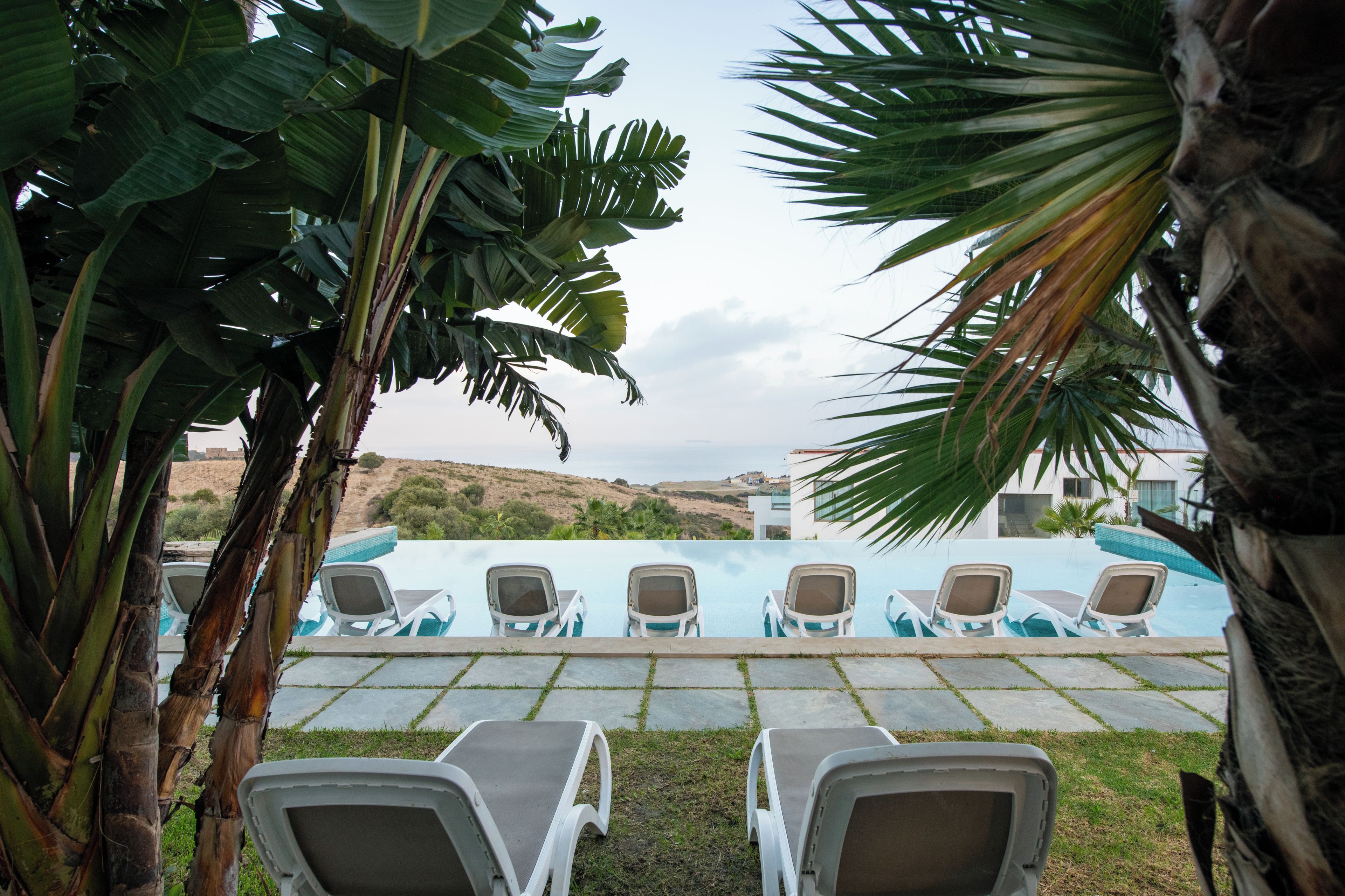 A pool area with lounge chairs and a view of the landscape.