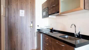 Una cocina moderna con armarios de madera, encimera negra, pileta de acero inoxidable y un microondas.