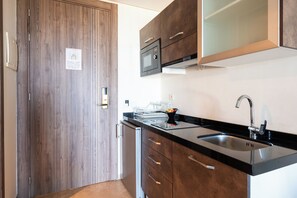 Een moderne keuken met houten kastjes, een zwart aanrecht, een roestvrijstalen spoelbak en een magnetron.