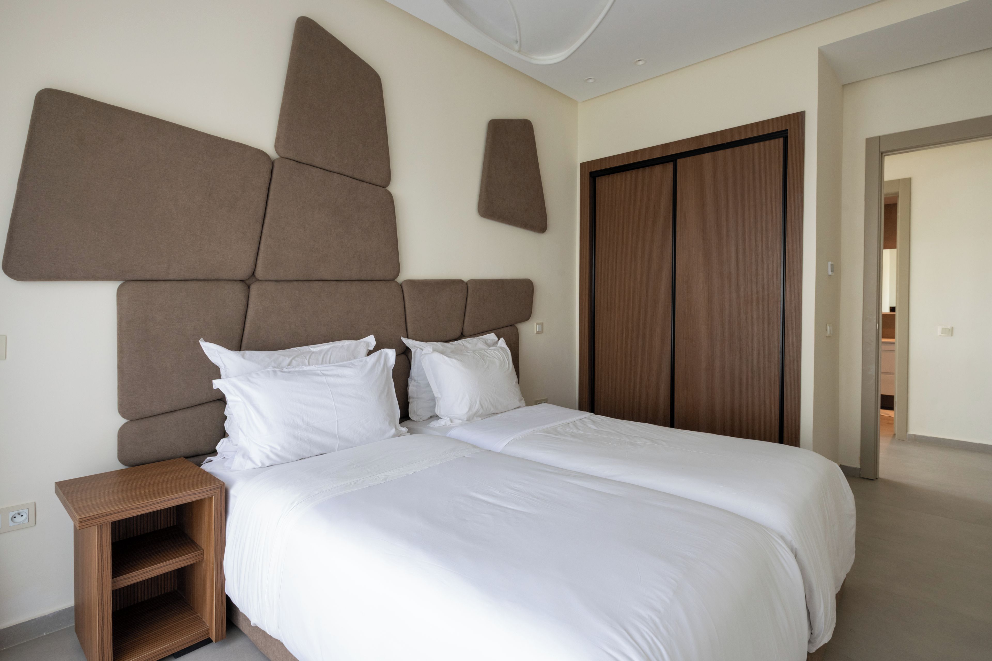 A bedroom with a large bed, a wooden nightstand, and a wardrobe.