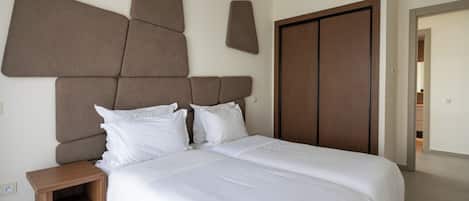 A bedroom with a large bed, a wooden nightstand, and a wardrobe.