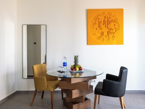A modern dining area with a glass table, two chairs, a fruit bowl, and a water bottle. - Le Tanger By Mnar Palm (Al Bahraoyine)