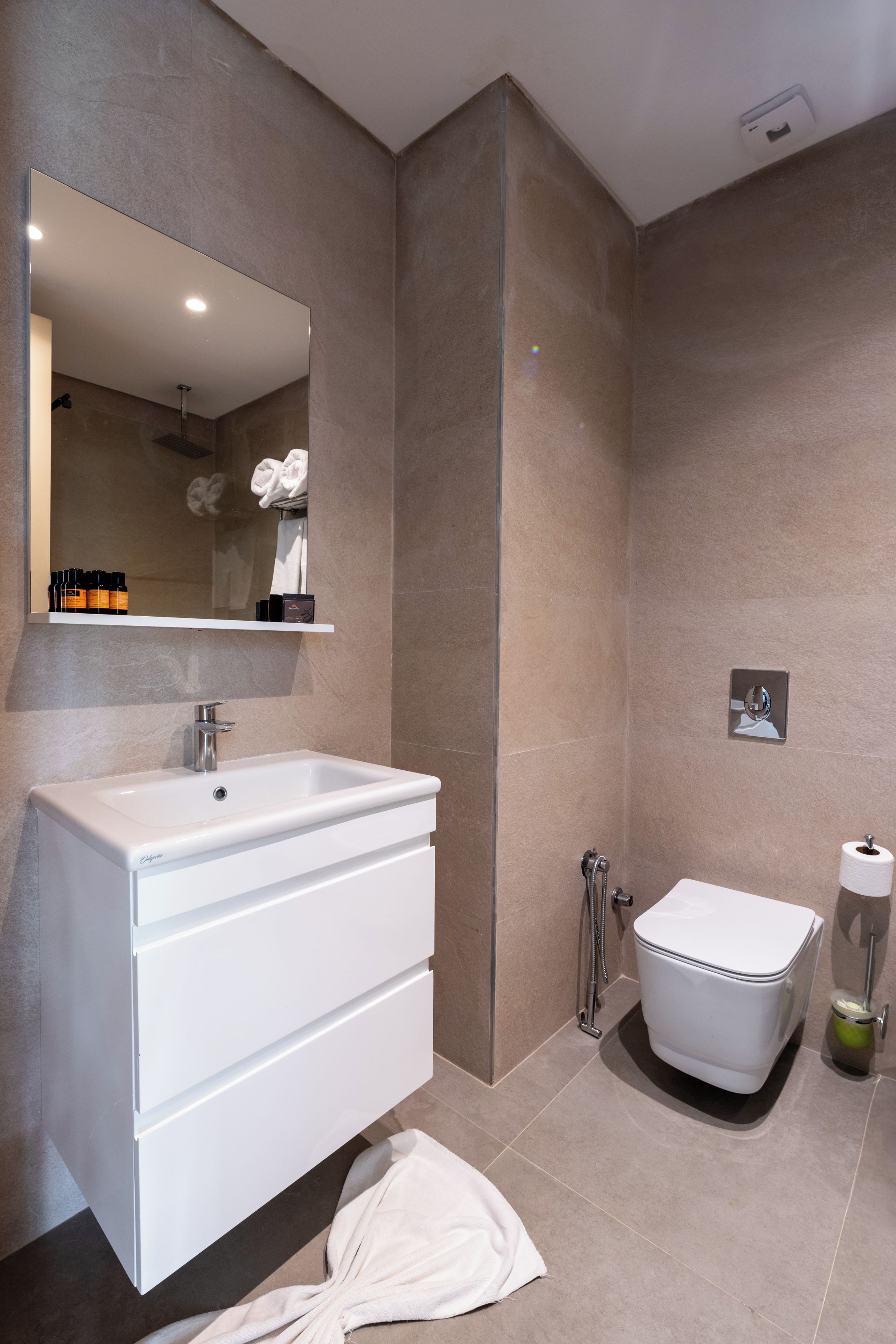 Een moderne badkamer met een wit wastafel, spiegel en toilet.