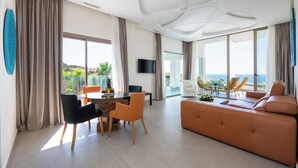 A modern living room with a sofa, dining table, chairs, and a TV. - Le Tanger By Mnar Palm (Al Bahraoyine)