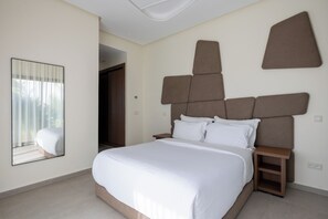 A modern hotel room with a large bed, a bedside table, and a mirror on the wall. - Le Tanger By Mnar Palm (Al Bahraoyine)