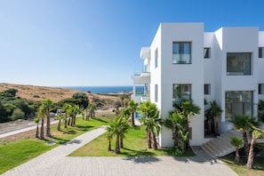 A modern white building with a paved driveway and palm trees, overlooking a coastal landscape. - Le Tanger By Mnar Palm (Al Bahraoyine)
