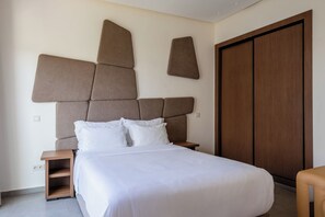 A modern hotel room with a large bed, a wooden nightstand, and a wardrobe. - Le Tanger By Mnar Palm (Al Bahraoyine)